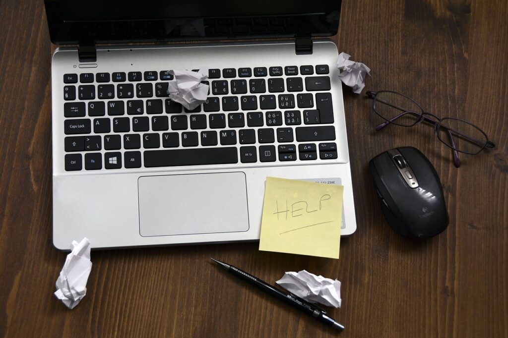 Image of a laptop with a sticky note on it that says help.