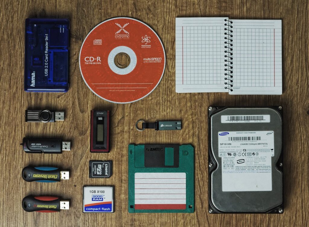 Image of various types of storage media laid out on a wooden desk for data backup service.